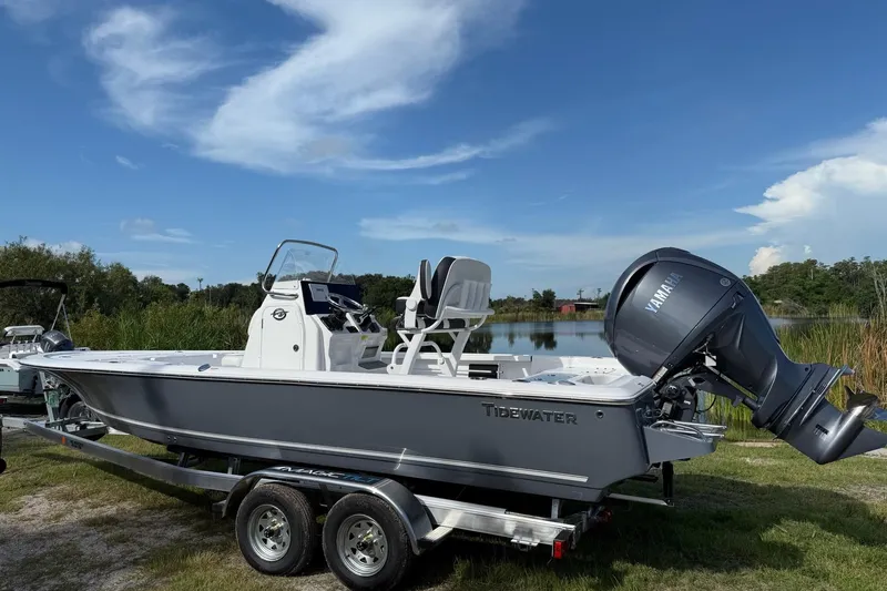 Slide: The Image of 2026 Tidewater 2110 Bay Max boat on trailer by a lake under blue sky. - 2