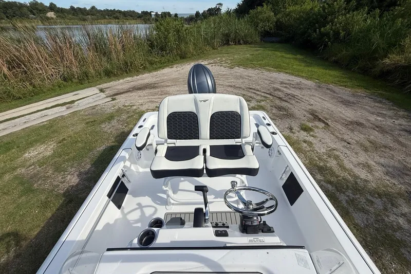 Slide: The Image of 2026 Tidewater 2110 Bay Max boat interior with dual seats and steering wheel, near a lake. - 22
