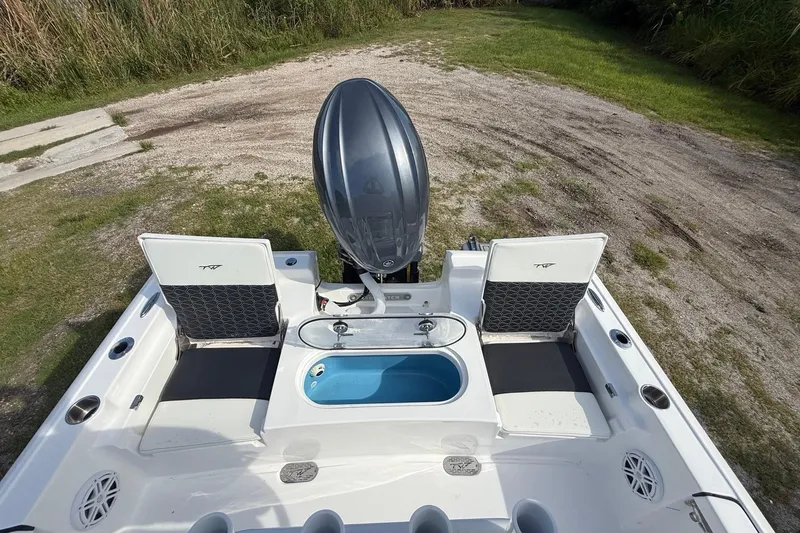 Slide: The Image of 2026 Tidewater 2110 Bay Max boat with outboard motor and seating, parked on grass. - 24