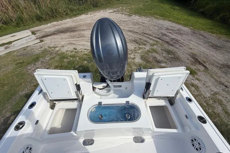 Slide: The Image of 2026 Tidewater 2110 Bay Max boat with open storage compartments and motor, on grassy terrain. - 25