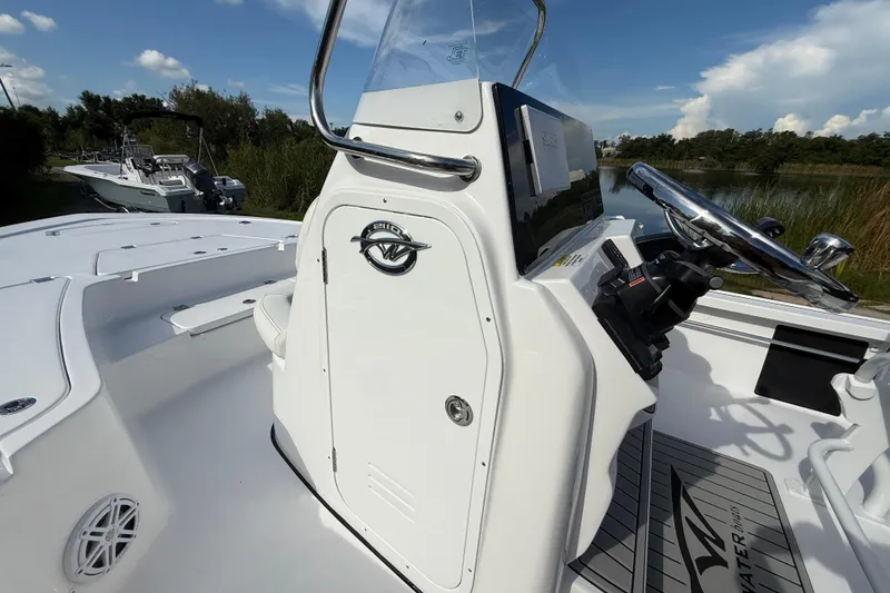 Slide: The Image of 2026 Tidewater 2110 Bay Max boat console with steering wheel, docked near lush greenery. - 29