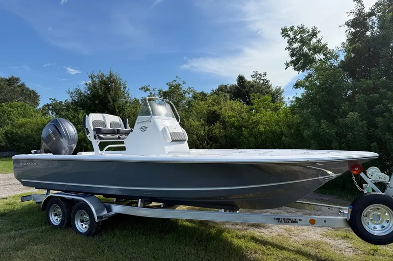 Slide: The Image of 2026 Tidewater 2110 Bay Max boat on trailer, parked outdoors with trees in background. - 9
