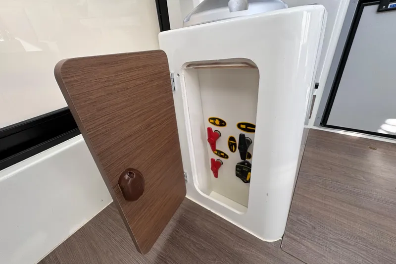 Slide: The Image of Open storage compartment on Jeanneau NC Sport 795 Series 2, 2026 model, with control switches. - 19