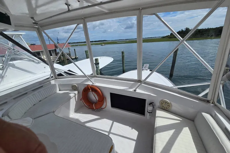 Slide: The Image of 1988 Topaz 44 Flybridge interior with seating, life preserver, and scenic water view. - 17