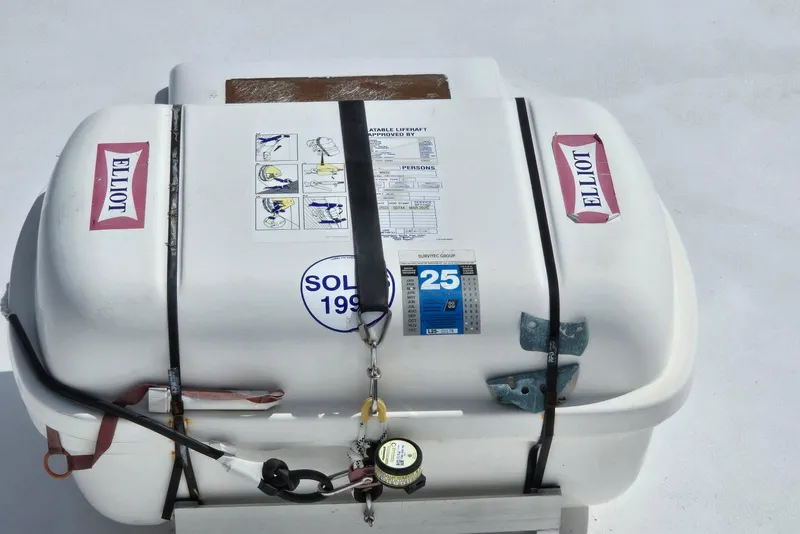 Slide: The Image of Life raft on 1988 Topaz 44 Flybridge boat, secured with straps and labeled "Elliot." - 21
