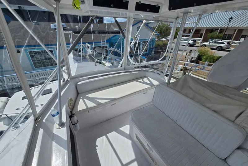 Slide: The Image of 1988 Topaz 44 Flybridge interior with white seating and marina view. - 22