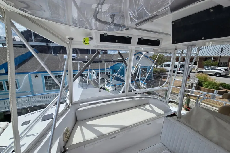 Slide: The Image of 1988 Topaz 44 Flybridge interior view with seating and marina backdrop. - 32