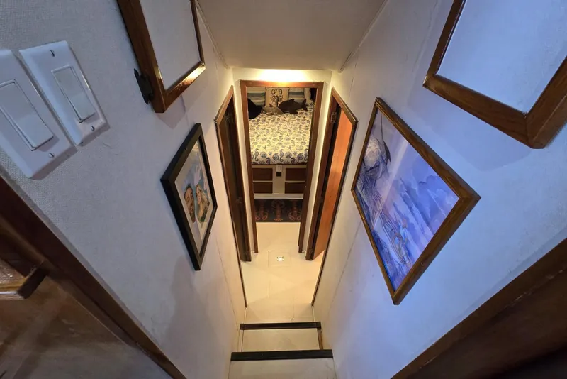 Slide: The Image of Narrow hallway in 1988 Topaz 44 Flybridge yacht with framed artwork and bedroom view. - 5
