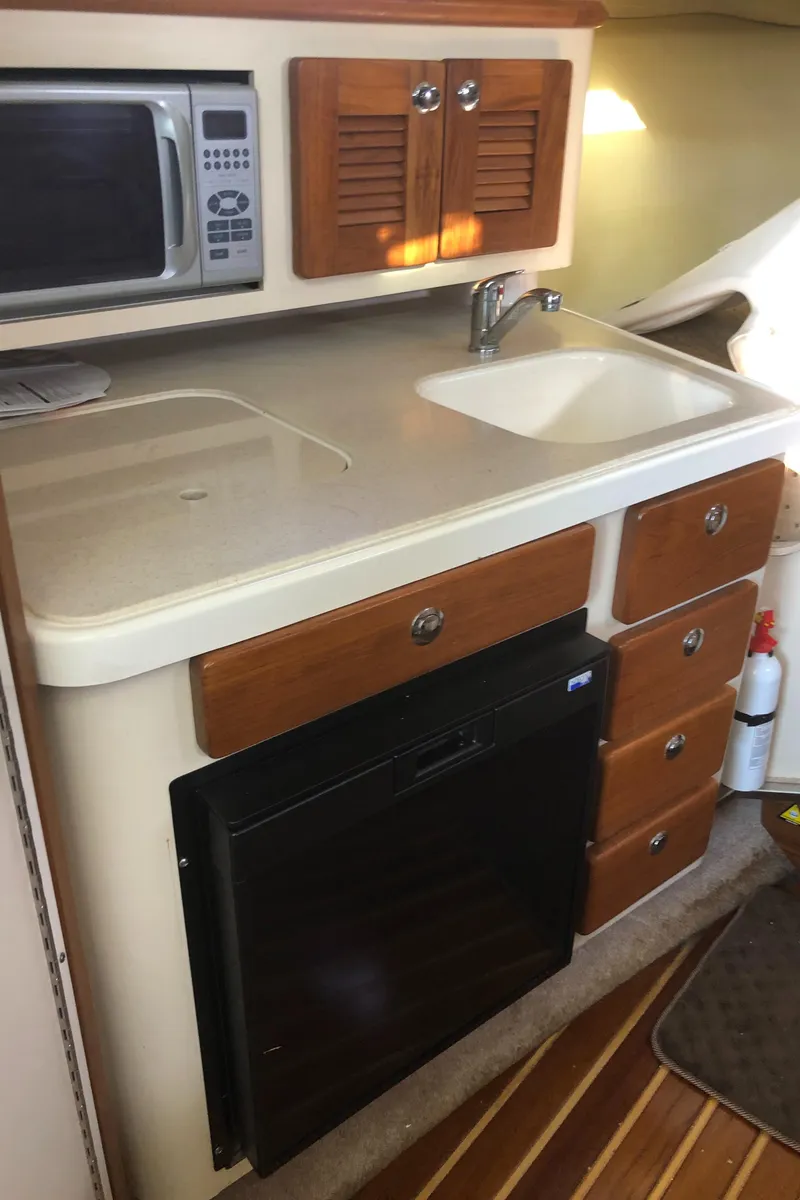 Slide: The Image of 2007 Pursuit 335 Offshore boat kitchen with sink, microwave, and wooden cabinets. - 31