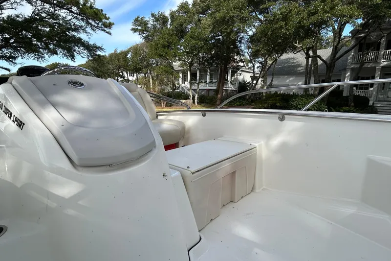 Slide: The Image of 2023 Boston Whaler 160 Super Sport boat interior with seating and storage, surrounded by trees. - 12