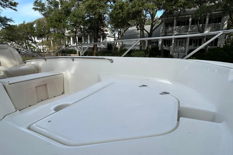 Slide: The Image of 2023 Boston Whaler 160 Super Sport boat interior with seating and railing, surrounded by trees. - 14