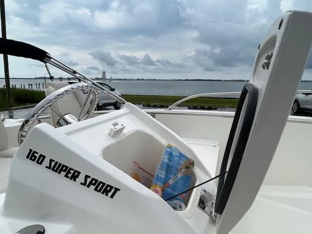 Slide: The Image of 2023 Boston Whaler 160 Super Sport interior with red storage box and white seats. - 7