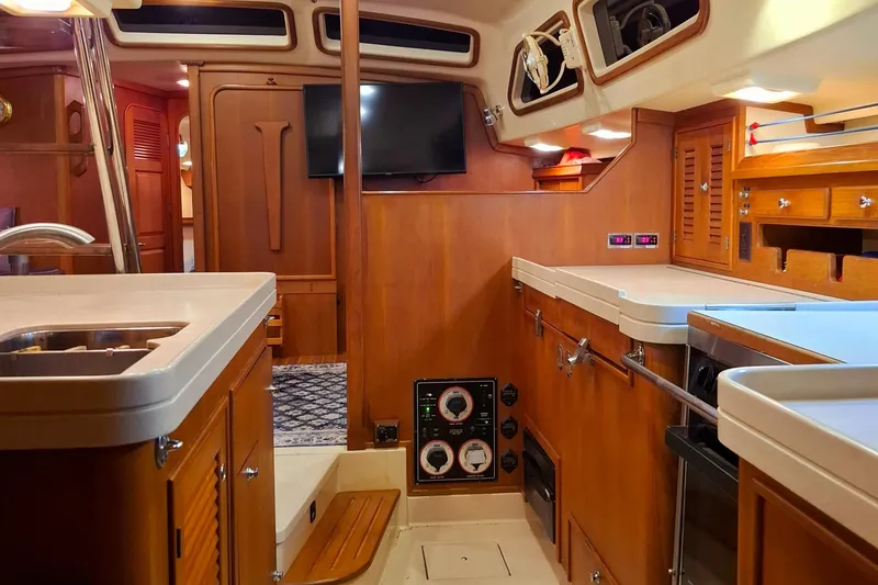 Slide: The Image of Interior of 2003 Island Packet 485 yacht, featuring a well-equipped galley and wooden cabinetry. - 16