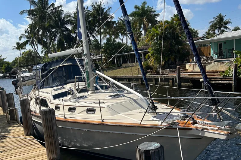 Slide: The Image of 2003 Island Packet 485 sailboat docked by palm trees and waterfront homes. - 4