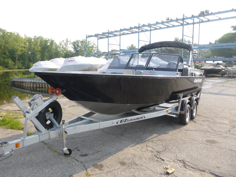 Slide: The Image of 2025 KingFisher 2125 Arrow Sport boat on trailer, parked outdoors near water. - 2
