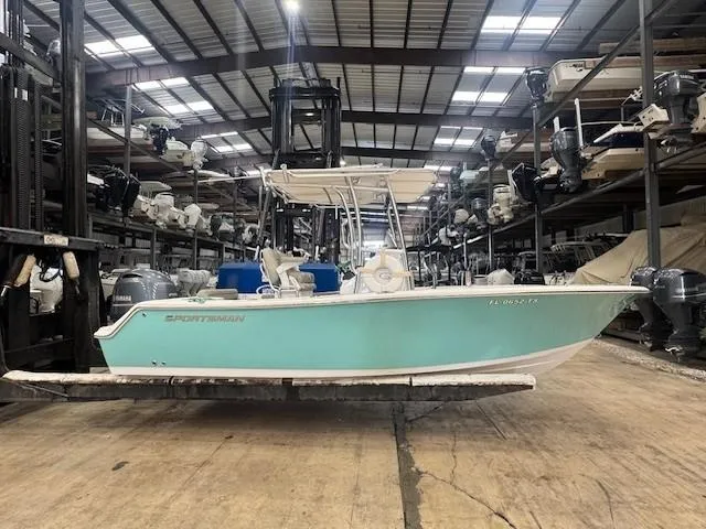 The Image of 2023 Sportsman 212 boat in storage facility, turquoise hull, indoor warehouse setting. - 1