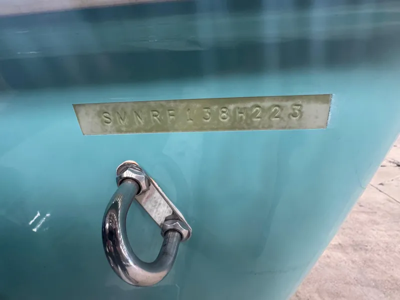 Slide: The Image of 2023 Sportsman 212 boat hull identification number and metal cleat on blue surface. - 13