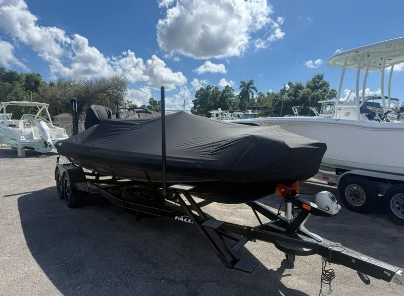 Slide: The Image of 2025 Falcon Boats 21 Predator covered on trailer under a blue sky. - 33