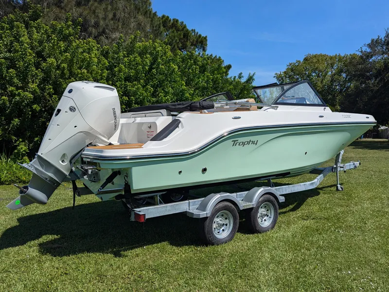 Slide: The Image of 2026 Bayliner Trophy T22SC boat on trailer, parked on grass, with outboard motor. - 2