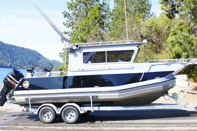 The Image of 2005 ACB 27 boat on trailer by scenic lake and forest background. - 0