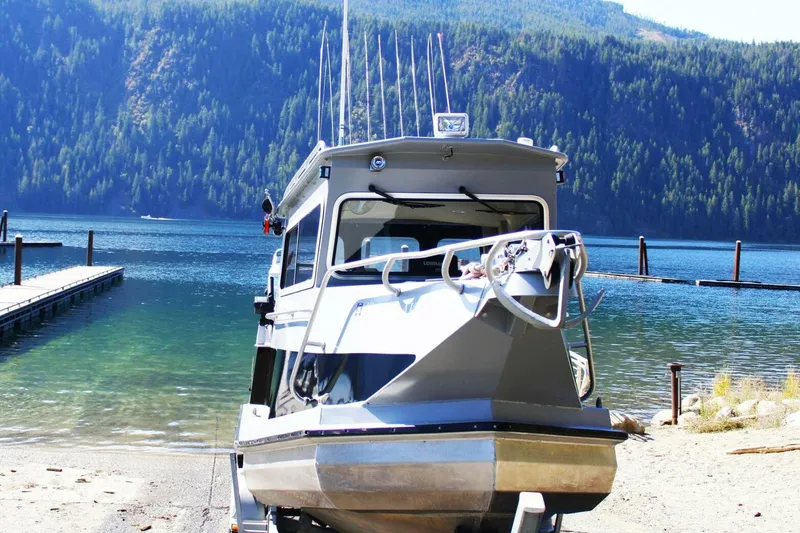 Slide: The Image of Boat on shore near dock with scenic forested lake background, ACB 27, 2005 model. - 1
