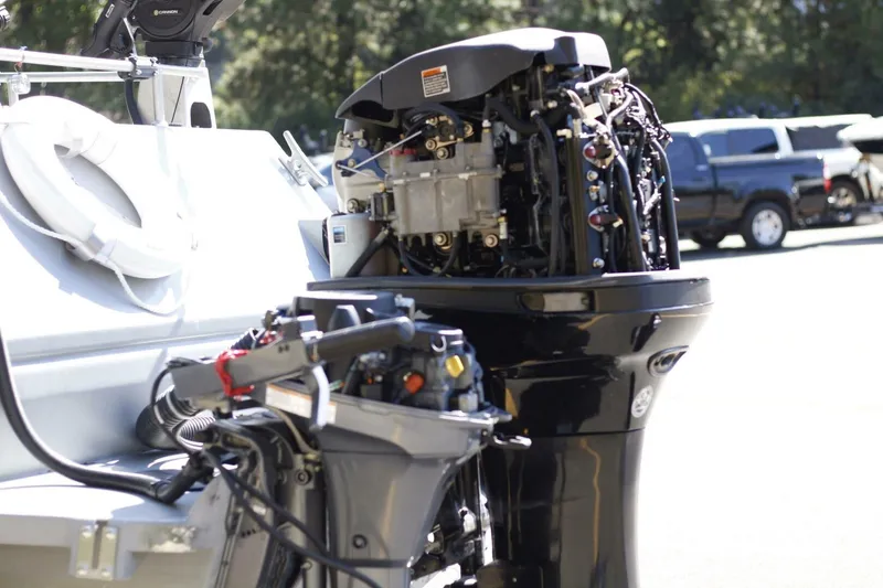 Slide: The Image of Open boat engine on ACB 27, 2005 model, with visible components and parked vehicles in background. - 21
