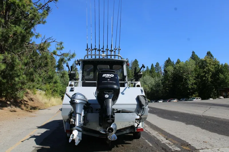 Slide: The Image of 2005 ACB 27 boat with multiple fishing rods, parked on a scenic roadside. - 51