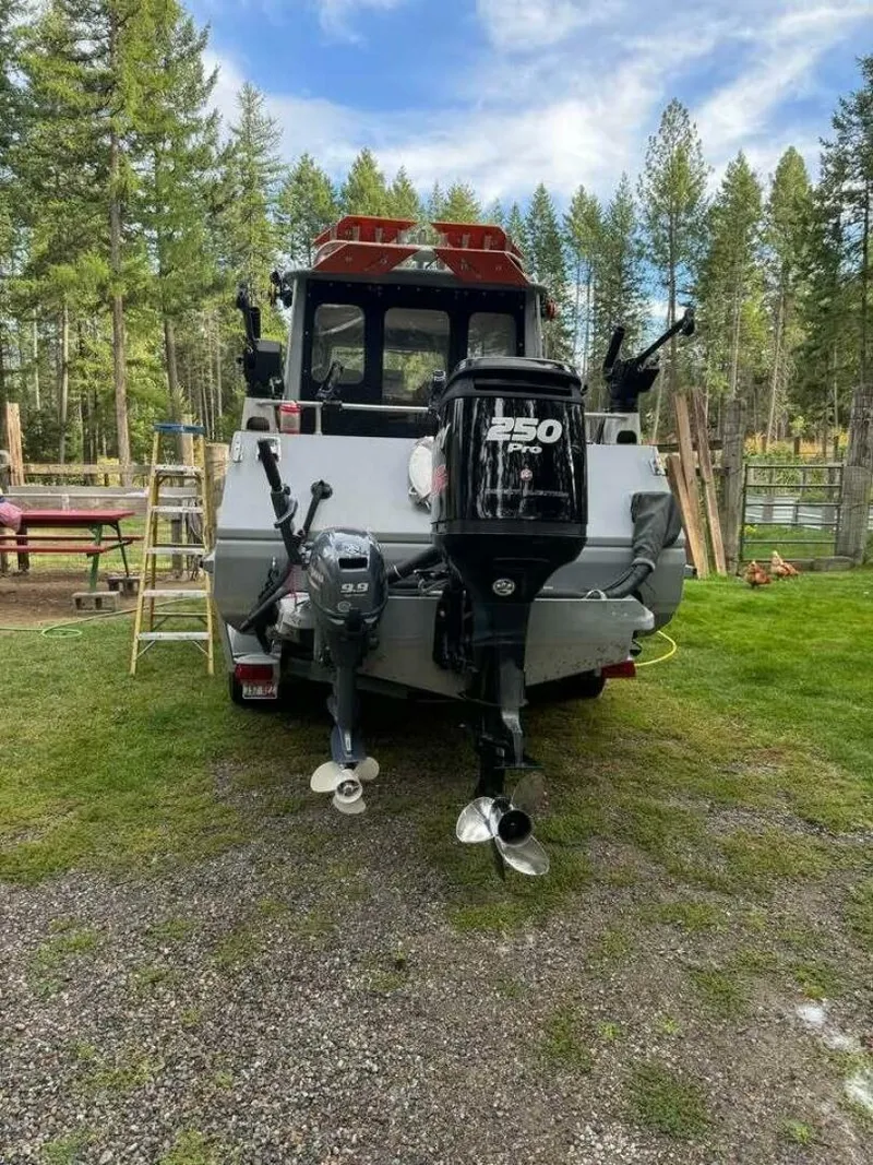 Slide: The Image of Rear view of a 2005 ACB 27 boat with dual outboard motors in a wooded area. - 54