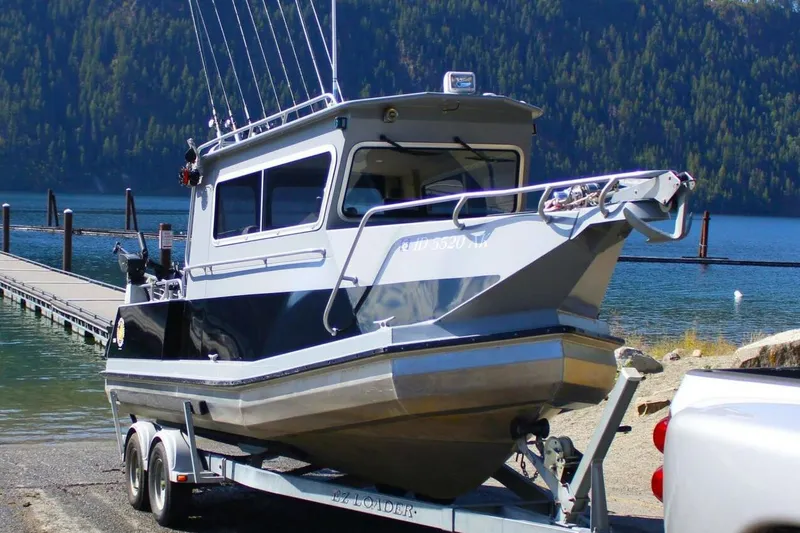 Slide: The Image of 2005 ACB 27 boat on trailer by lake, surrounded by forested hills. - 7