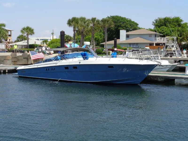 Slide: The Image of 1988 Magnum 40 Sport boat docked in a marina, featuring a blue hull and American flag. - 0