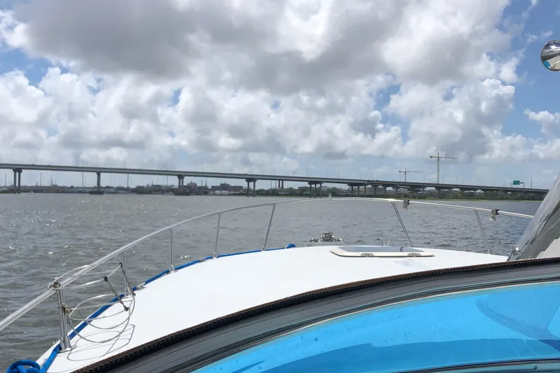 Slide: The Image of 1988 Magnum 40 Sport boat cruising under cloudy sky near a bridge. - 10