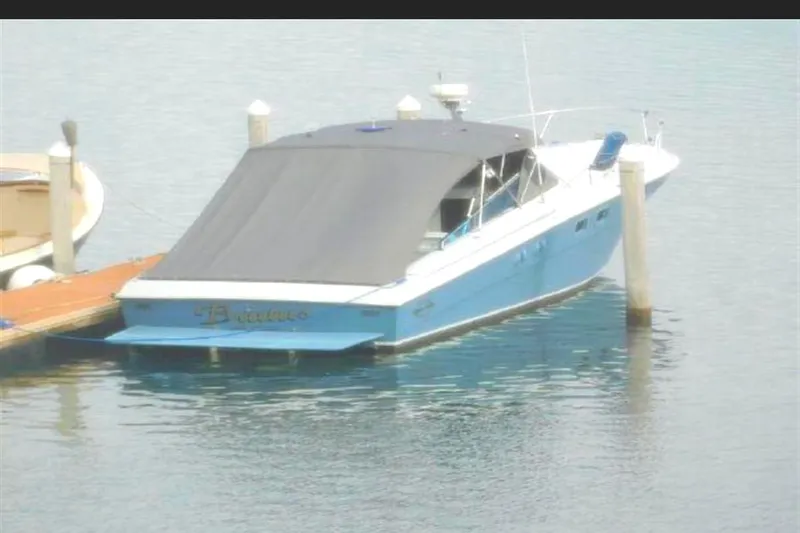 Slide: The Image of 1988 Magnum 40 Sport boat docked, covered with a black canopy, in calm waters. - 11