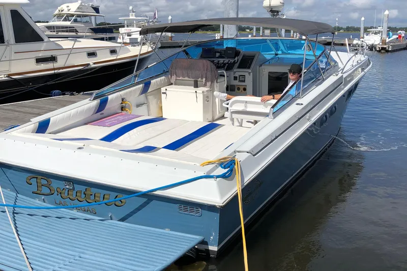Slide: The Image of 1988 Magnum 40 Sport boat docked, featuring blue and white design with canopy and seating. - 5