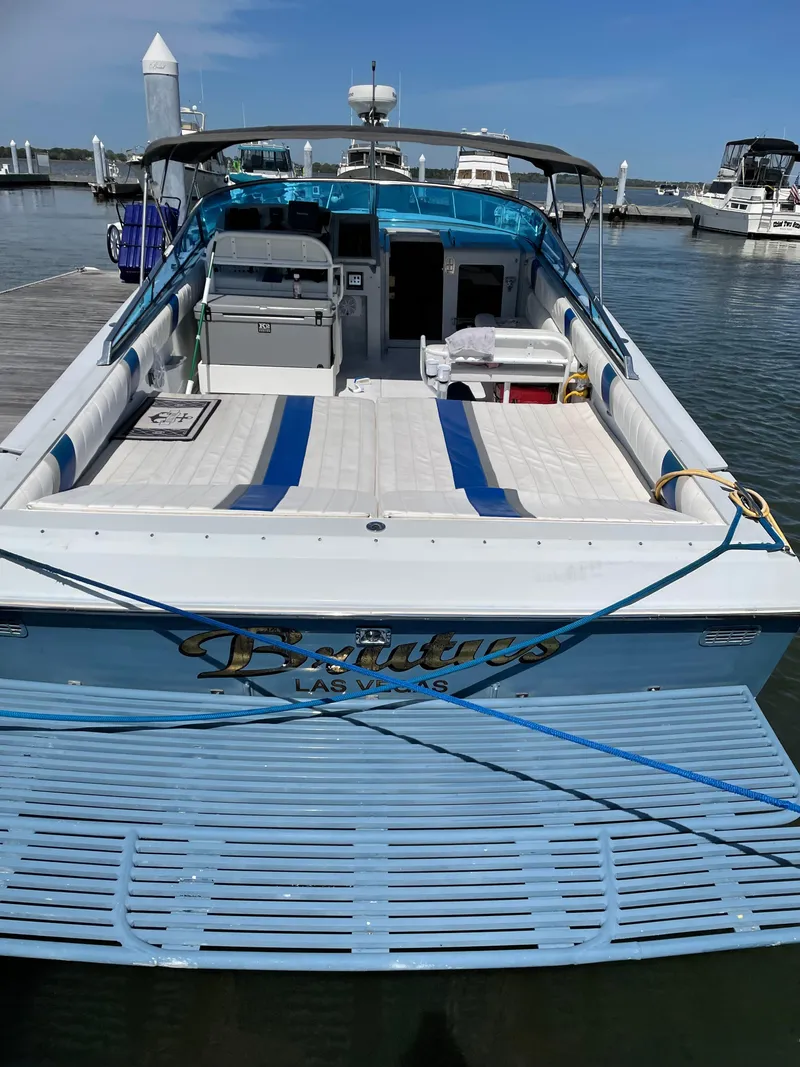 Slide: The Image of 1988 Magnum 40 Sport boat docked, featuring spacious deck and seating, with "Brutus" name visible. - 6