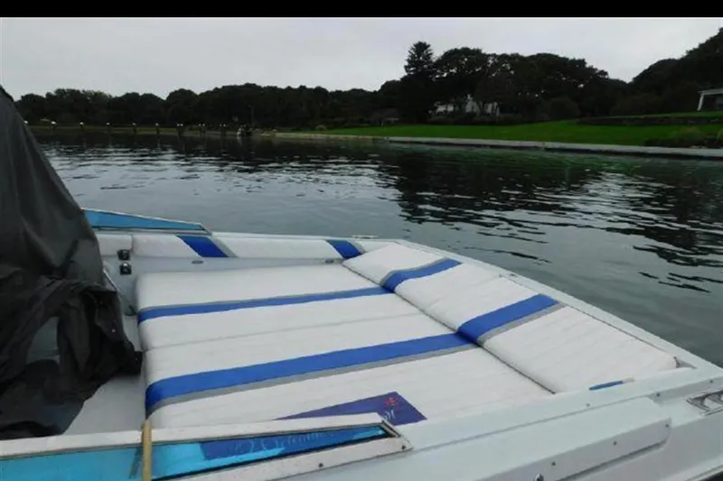 Slide: The Image of 1988 Magnum 40 Sport boat with blue and white seating on calm water. - 8