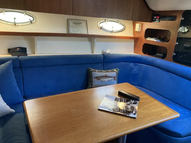 Slide: The Image of Interior of 2000 Tiara Yachts 3100 Open with blue seating and wooden table. - 15