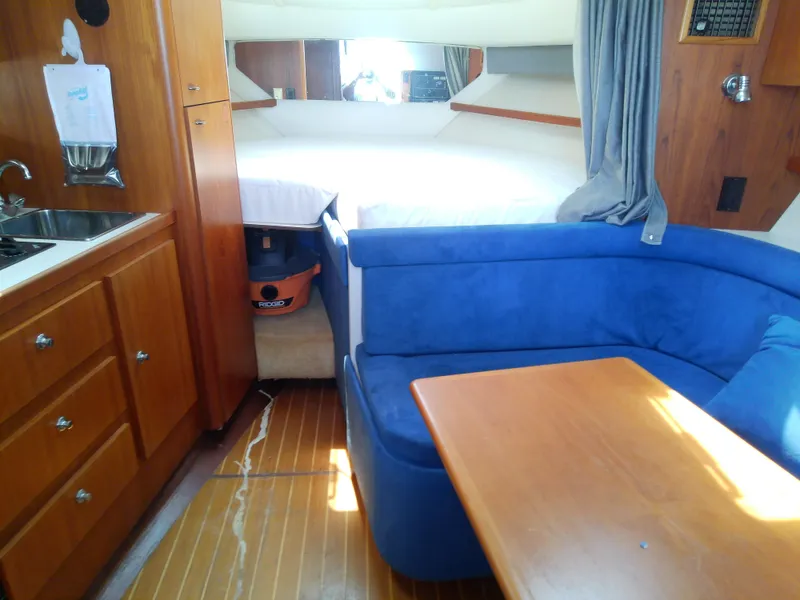 Slide: The Image of Interior of 2000 Tiara Yachts 3100 Open with blue seating and wooden cabinetry. - 44