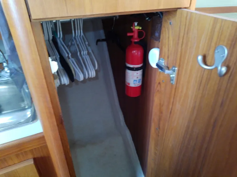 Slide: The Image of Open wooden cabinet on 2000 Tiara Yachts 3100 Open, showing hangers and fire extinguisher. - 47