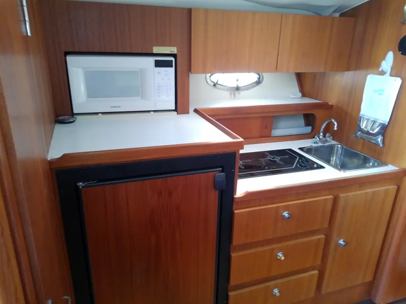 Slide: The Image of Compact kitchen in 2000 Tiara Yachts 3100 Open, featuring microwave, sink, and stove. - 48