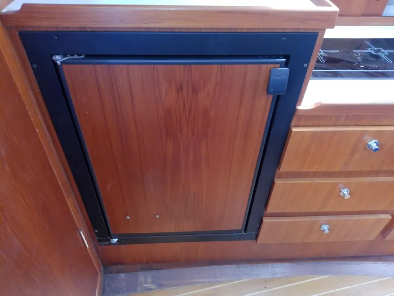 Slide: The Image of Wooden cabinetry in a 2000 Tiara Yachts 3100 Open, featuring a built-in fridge and drawers. - 49