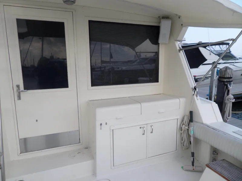 Slide: The Image of 1987 Hatteras 42 Convertible yacht deck with storage cabinets and docked boats in background. - 10