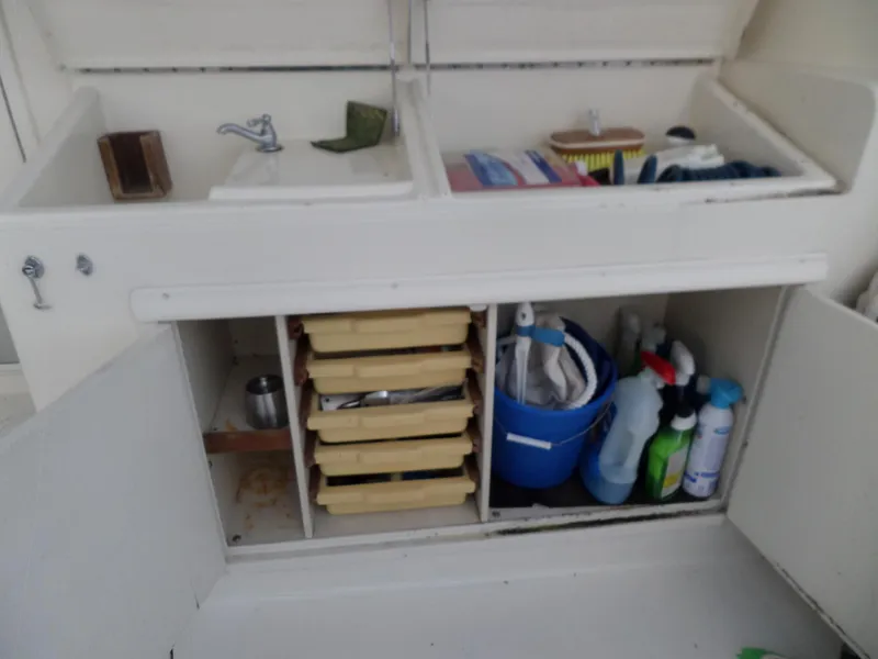 Slide: The Image of 1987 Hatteras 42 Convertible boat interior storage with sink, cleaning supplies, and drawers. - 13