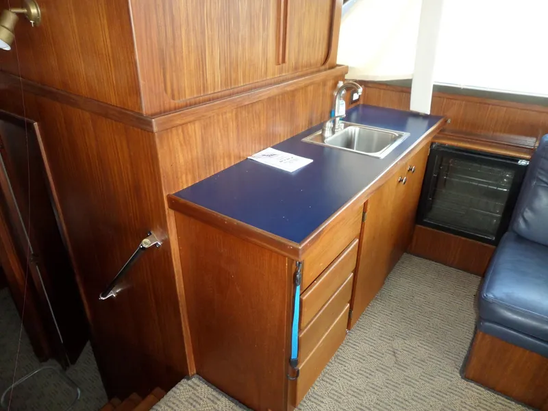 Slide: The Image of 1987 Hatteras 42 Convertible interior with wooden cabinetry and compact kitchen area. - 17