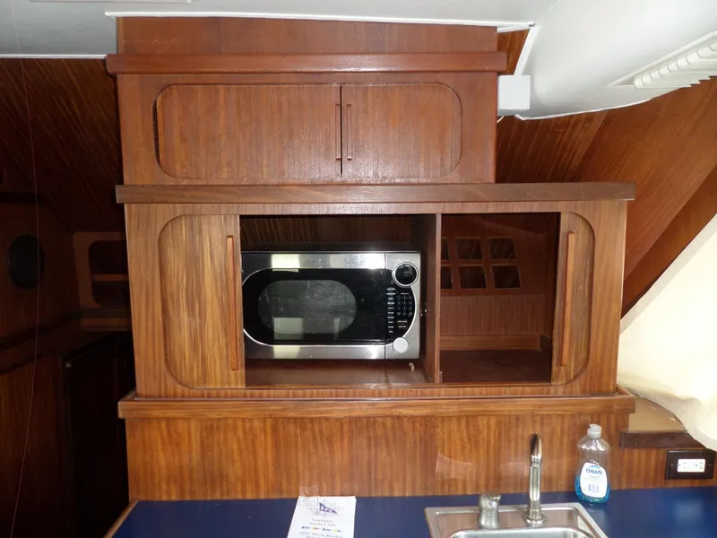 Slide: The Image of 1987 Hatteras 42 Convertible yacht kitchen with microwave and wooden cabinetry. - 24
