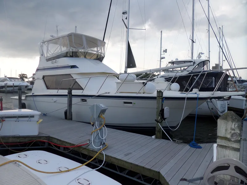 Slide: The Image of 1987 Hatteras 42 Convertible yacht docked at marina under cloudy sky. - 3