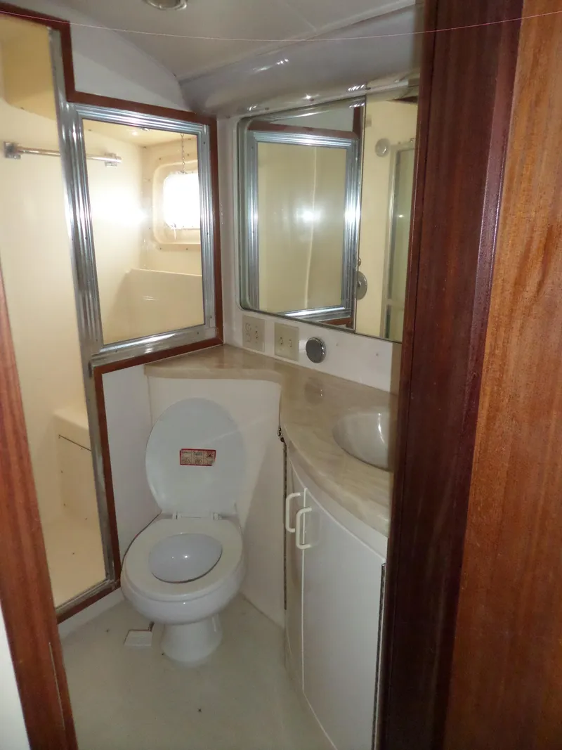 Slide: The Image of 1987 Hatteras 42 Convertible yacht bathroom with toilet, sink, and mirrored cabinet. - 30