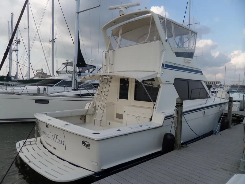 Slide: The Image of 1987 Hatteras 42 Convertible yacht docked at marina, featuring spacious deck and flybridge. - 4