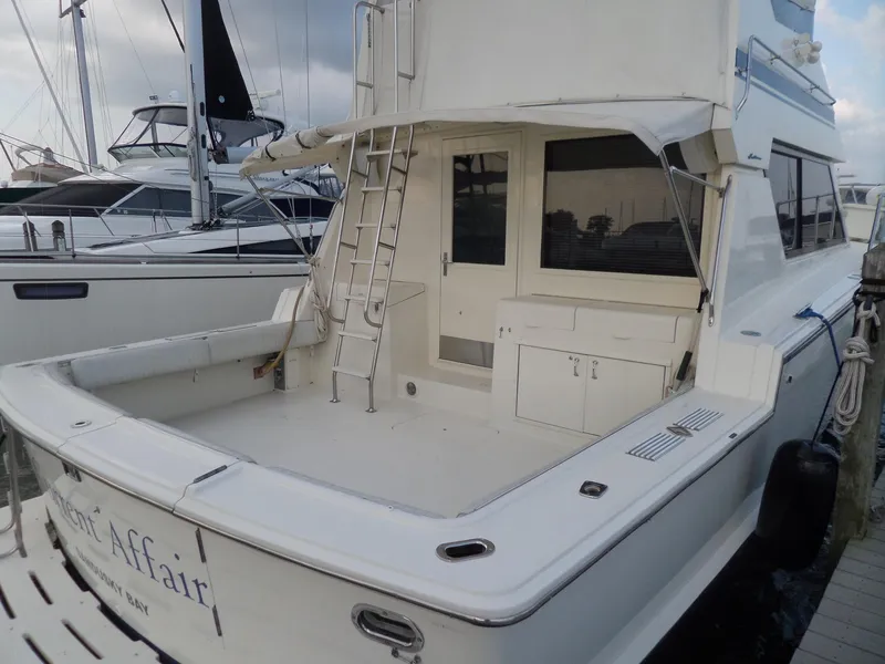 Slide: The Image of 1987 Hatteras 42 Convertible yacht docked, featuring spacious deck and ladder access. - 5