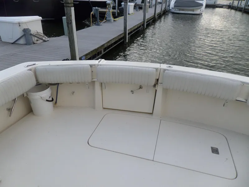 Slide: The Image of 1987 Hatteras 42 Convertible boat deck at marina, featuring white seating and storage compartments. - 8