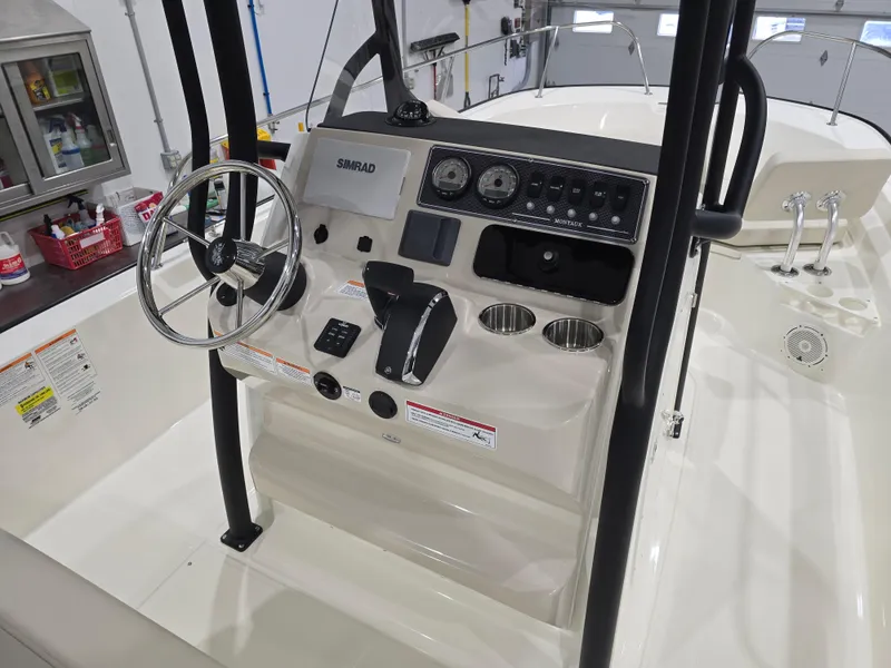 Slide: The Image of 2025 Boston Whaler 210 Montauk boat console with steering wheel and controls in a garage setting. - 13